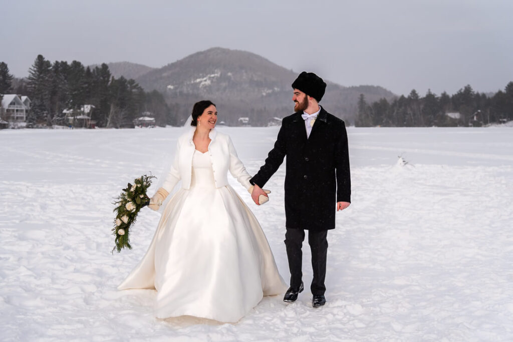 wedding couple holding hands on mirror lake in Lake Placid