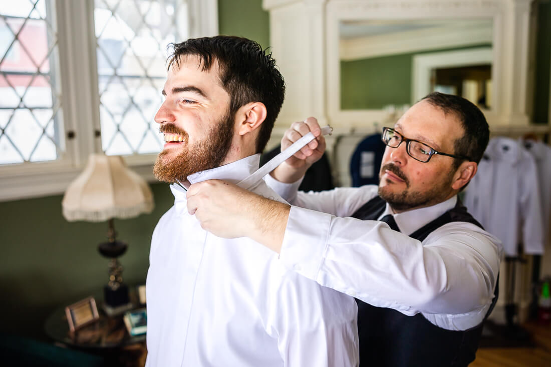 Best man helping with a bow tie before a hotel saranac wedding
