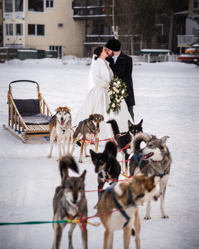 couple kissing with dog sled team on mirror lake in Lake Placid